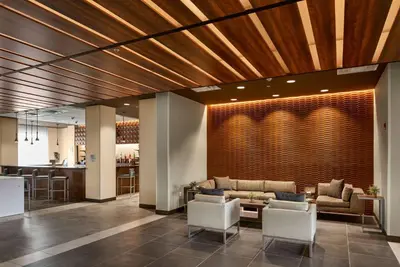 a lobby with a couch and chairs and a bar at Wingate by Wyndham Hurricane WV in Hurricane