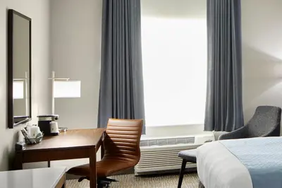 a hotel room with a desk and a bed at Wingate by Wyndham Hurricane WV in Hurricane