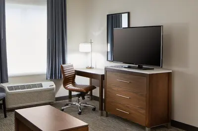 a hotel room with a desk and a flat screen tv at Wingate by Wyndham Hurricane WV in Hurricane