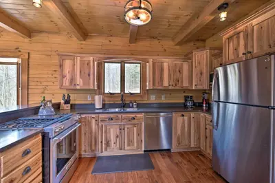 a kitchen with wooden cabinets and a stainless steel refrigerator at Family-Friendly Warsaw Cabin with Deck and Fireplace! in Warsaw