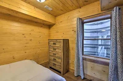 a log cabin bedroom with a bed and a window at Family-Friendly Warsaw Cabin with Deck and Fireplace! in Warsaw
