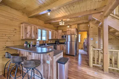 a kitchen with a large island in a log cabin at Family-Friendly Warsaw Cabin with Deck and Fireplace! in Warsaw