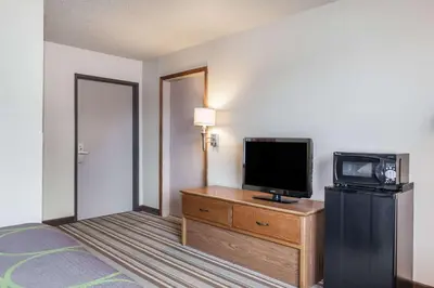 a hotel room with a bed and a television on a dresser at Super 8 by Wyndham Dunbar/Charleston Area in Charleston
