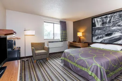 a hotel room with a bed and a chair at Super 8 by Wyndham Dunbar/Charleston Area in Charleston