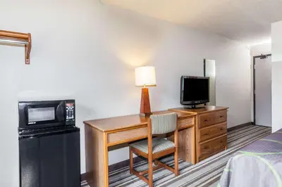 a hotel room with a desk with a microwave and a television at Super 8 by Wyndham Dunbar/Charleston Area in Charleston