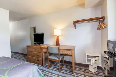 a hotel room with a desk with a television and a bed at Super 8 by Wyndham Dunbar/Charleston Area in Charleston