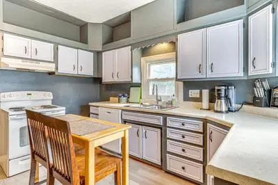 a kitchen with white cabinets and a wooden table at The Junction Victorian Home in Quaint Fortville! in Fortville