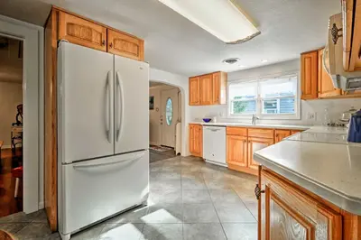 a kitchen with a white refrigerator and wooden cabinets at Ottawa Lake Home with BBQ and Patio, 15 Mi to Toledo in Sylvania