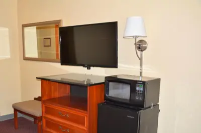 a room with a television and a microwave and a tv and a lamp at Buckeye Inn Express in Columbus