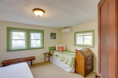 a bedroom with a bed and a dresser and two windows at Spacious Lakeside Cottage - 2 Miles to Marblehead! in Lakeside