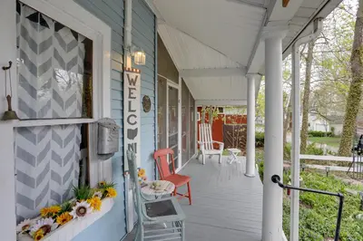 a front porch of a blue house with a red chair at Spacious Lakeside Cottage - 2 Miles to Marblehead! in Lakeside