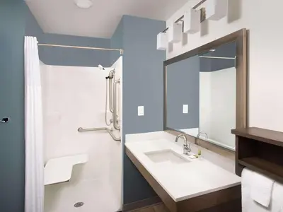 a bathroom with a sink and a mirror at WoodSpring Suites Toledo Maumee in Maumee