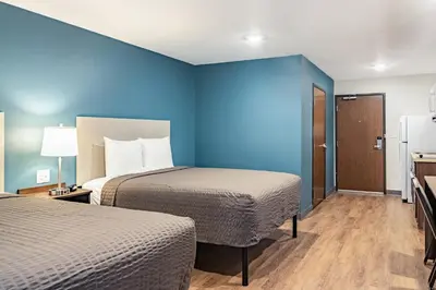 a room with two beds and a blue wall at WoodSpring Suites Toledo Maumee in Maumee