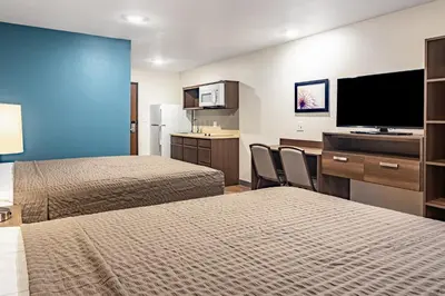 a hotel room with two beds and a flat screen tv at WoodSpring Suites Toledo Maumee in Maumee