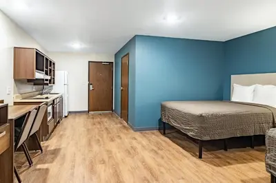 a small room with a bed and a blue wall at WoodSpring Suites Toledo Maumee in Maumee