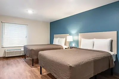 two beds in a room with blue walls at WoodSpring Suites Toledo Maumee in Maumee
