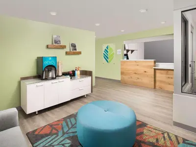 a waiting room with a blue ottoman in a room at WoodSpring Suites Toledo Maumee in Maumee