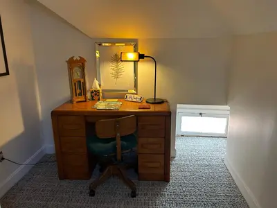 a desk with a chair with a mirror and a lamp at 50 Lincoln Short North Bed & Breakfast in Columbus