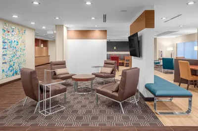 a waiting room with chairs and a table and a tv at TownePlace Suites Cincinnati Fairfield in Fairfield