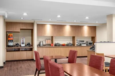 a conference room with tables and chairs and a kitchen at TownePlace Suites Cincinnati Fairfield in Fairfield
