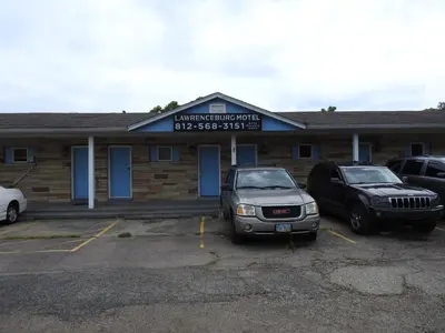 a building with two cars parked in a parking lot at LAWRENCEBURG MOTEL in Greendale