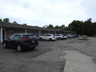 a parking lot with cars parked in front of a building at LAWRENCEBURG MOTEL in Greendale
