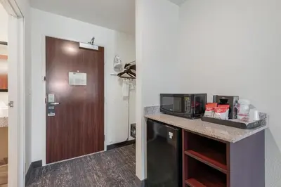 a room with a counter with a microwave and a door at Cobblestone Hotel & Suites - Urbana in Urbana