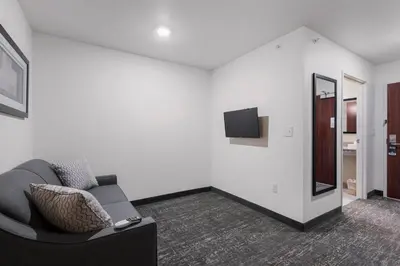 a living room with a couch and a mirror at Cobblestone Hotel & Suites - Urbana in Urbana