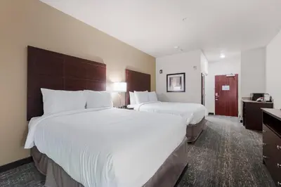 a hotel room with two beds and a desk at Cobblestone Hotel & Suites - Urbana in Urbana