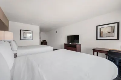 a hotel room with two beds and a desk at Cobblestone Hotel & Suites - Urbana in Urbana