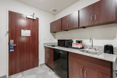 a kitchen with wooden cabinets and a sink at Cobblestone Hotel & Suites - Urbana in Urbana