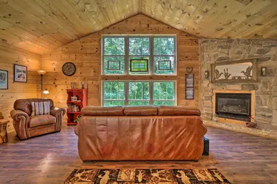 a living room with a leather couch and a fireplace at Butler Cabin on 19 Acres with Hot Tub and Fire Pit! in Butler