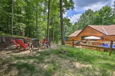 a backyard with chairs and a table and a log cabin at Butler Cabin on 19 Acres with Hot Tub and Fire Pit! in Butler