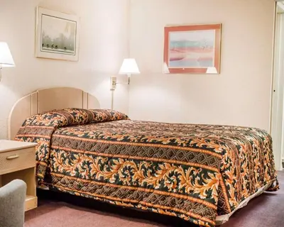 a hotel room with a bed with a blanket on it at Rodeway Inn Findlay University Area in Findlay