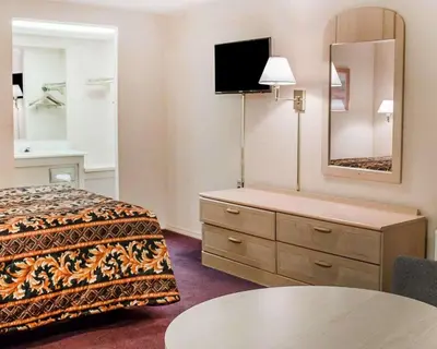 a hotel room with a bed and a dresser with a mirror at Rodeway Inn Findlay University Area in Findlay