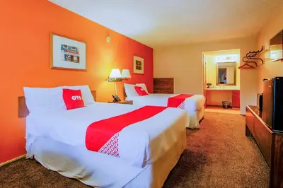 two beds in a hotel room with red walls at OYO Hotel Chapmanville Inn, WV - Hwy 119 in Chapmanville