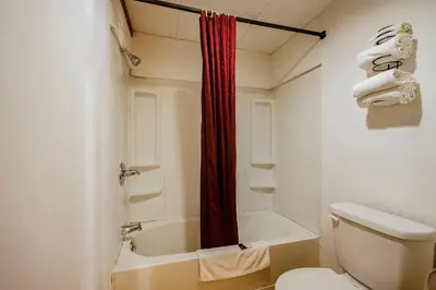 a bathroom with a white toilet and a red shower curtain at OYO Hotel Chapmanville Inn, WV - Hwy 119 in Chapmanville