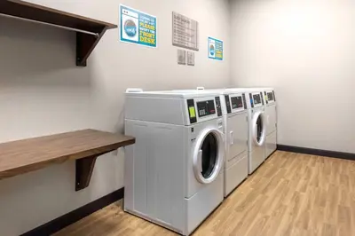 a laundry room with three washing machines and a table at Home2 Suites By Hilton Fort Wayne North in Sunnybrook Acres