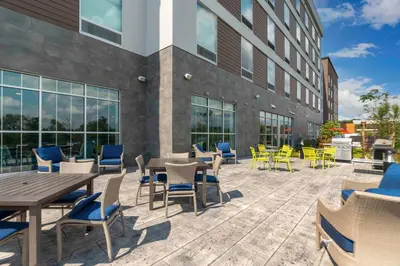 a patio with tables and chairs in front of a building at Home2 Suites By Hilton Fort Wayne North in Sunnybrook Acres