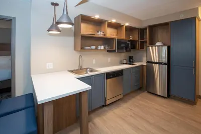 a kitchen with blue cabinets and a stainless steel refrigerator at Candlewood Suites - Cleveland South - Independence by IHG in Independence