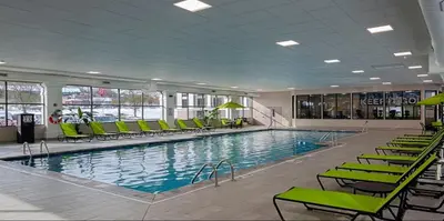 a large swimming pool with green chairs in a building at Candlewood Suites - Cleveland South - Independence by IHG in Independence