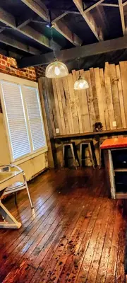 a room with a wooden floor and a table and two windows at Hocking Hills Rusty Lofts in Logan