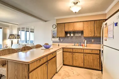 a kitchen with wooden cabinets and a white refrigerator at The Shores Condo with Beach Access Less Than 2 Mi to Dtwn! in Port Clinton
