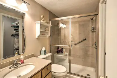 a bathroom with a shower and a toilet and a sink at The Shores Condo with Beach Access Less Than 2 Mi to Dtwn! in Port Clinton