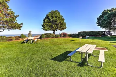 a row of picnic tables in a grass field at The Shores Condo with Beach Access Less Than 2 Mi to Dtwn! in Port Clinton