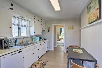 a kitchen with white cabinets and a sink and a table at Port Clinton Getaway - Walk to Beach and Restaurants in Port Clinton