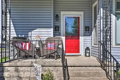 a porch with two chairs and a red door at Port Clinton Getaway - Walk to Beach and Restaurants in Port Clinton