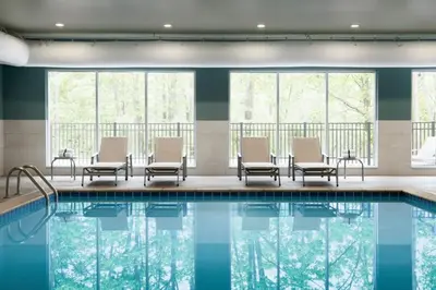 a pool in a hotel with chairs and windows at Holiday Inn Express & Suites Heath - Newark by IHG in Heath
