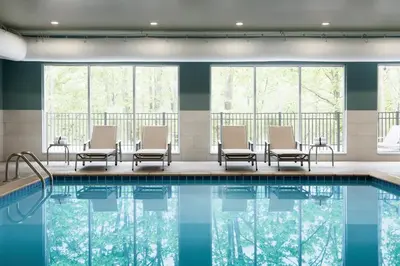 a pool in a hotel with chairs and windows at Holiday Inn Express & Suites Heath - Newark by IHG in Heath