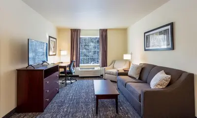 a living room with a couch and a desk in a hotel room at Cobblestone Inn & Suites - Brookville in Brookville